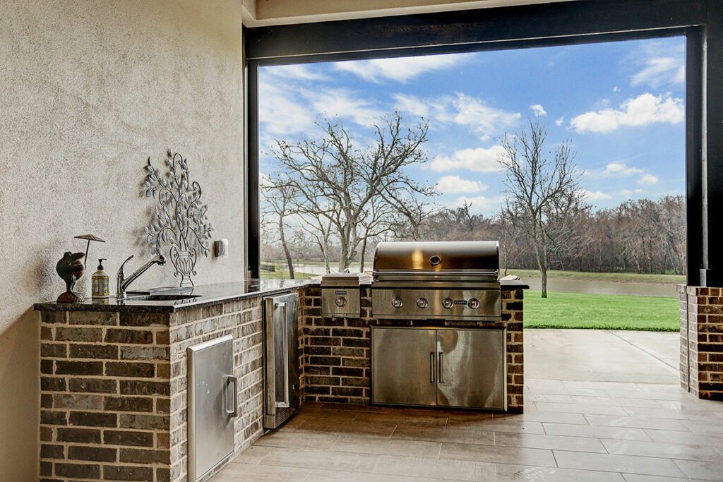 Outdoor Kitchen With Stainless Steel Grill And Stone Countertops