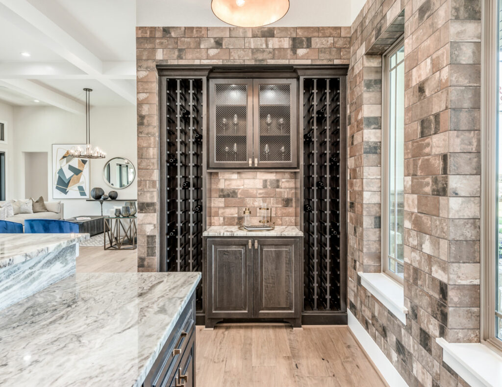 Sophisticated home wine bar featuring dark cabinetry and rustic brick wall accents.