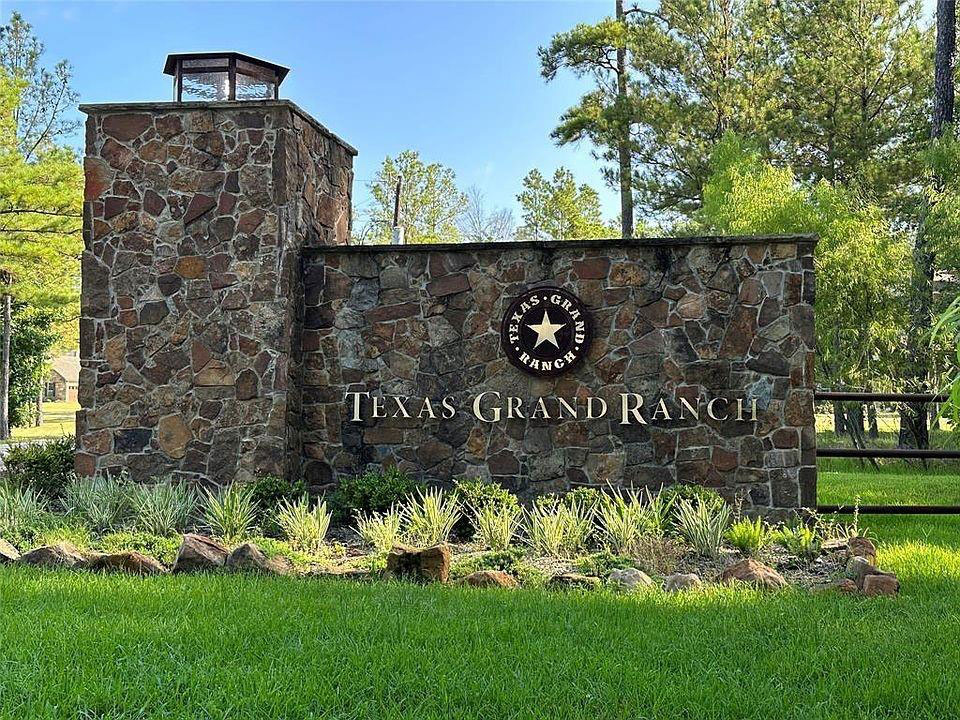 Stone monument sign for Texas Grand Ranch entrance with star logo and landscaping.