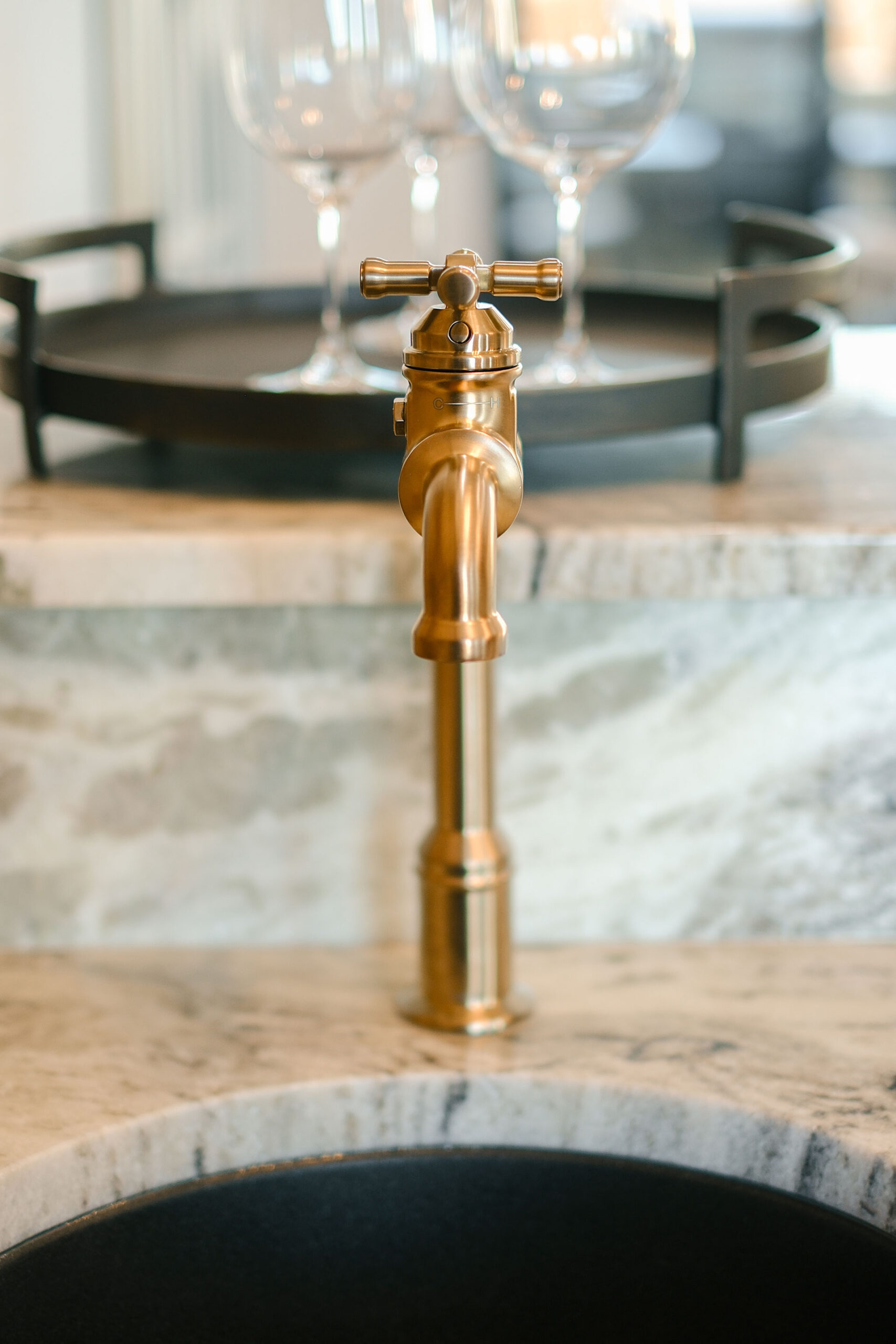 Gold kitchen faucet and marble countertop showcasing luxury custom home finishes.